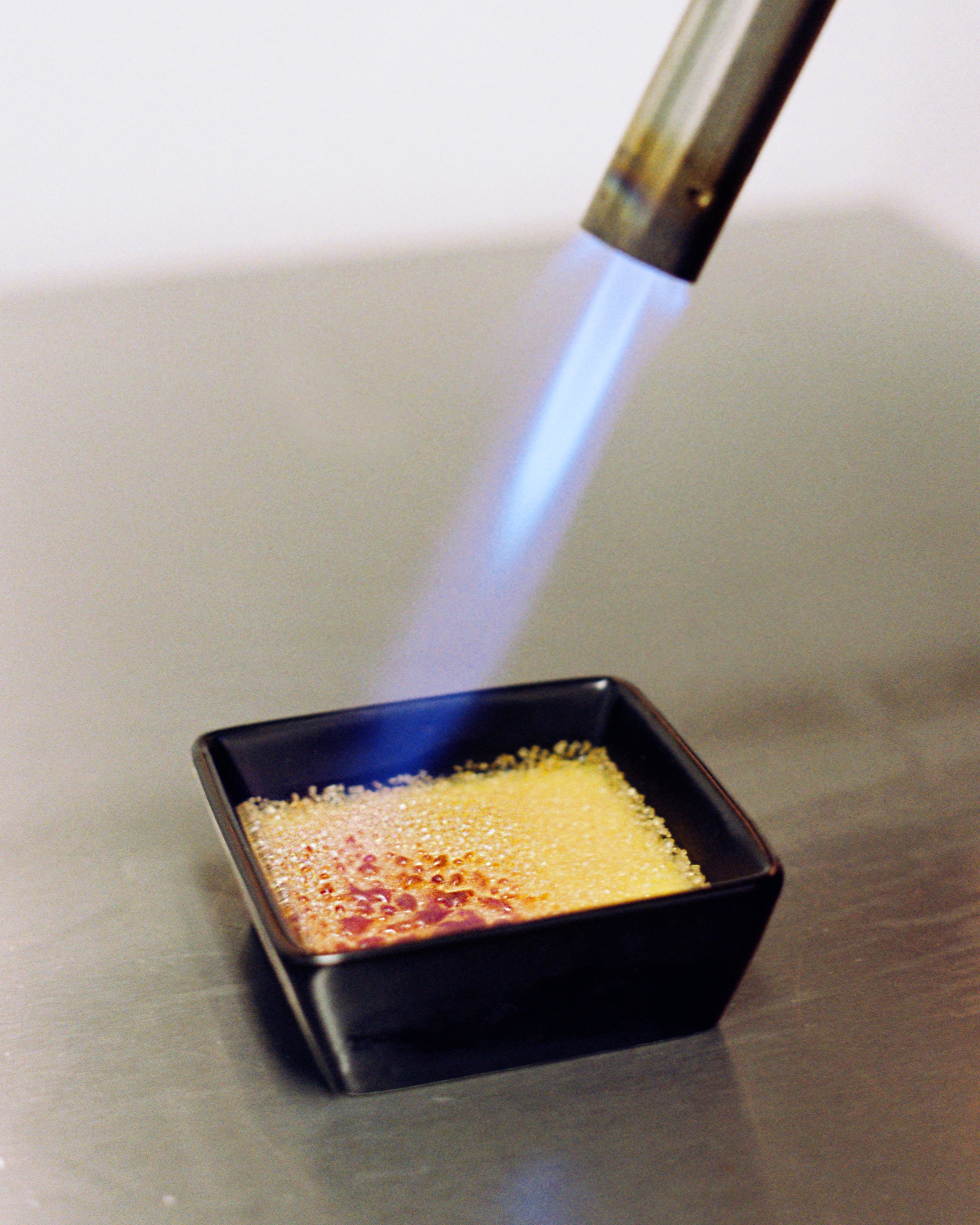 A flame caramelising the sugar on a crème brûlée